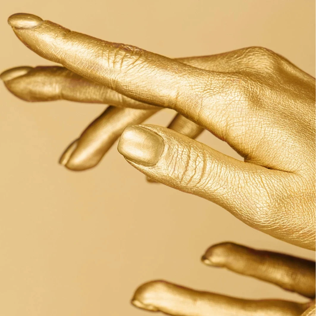 Gold hands on a beige background